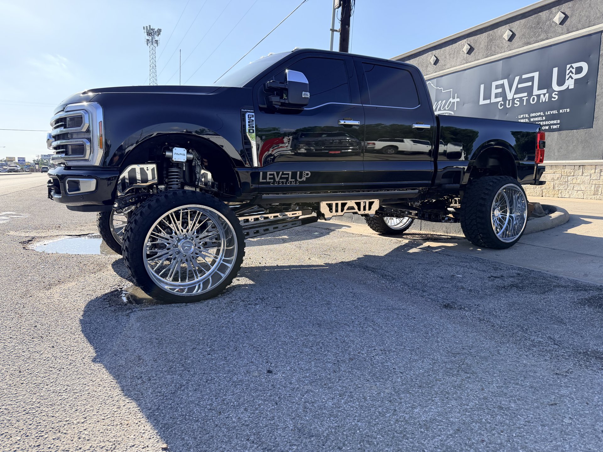 Blacked-out Ford Super Duty with massive suspension lift and chrome spoked wheels, Level Up Customs, Alvin TX