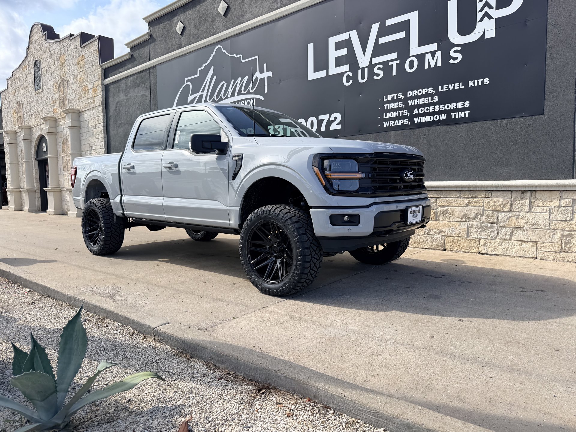 Silver Ford F-150 with custom wheel and tire package in front of Level Up Customs, Alvin TX