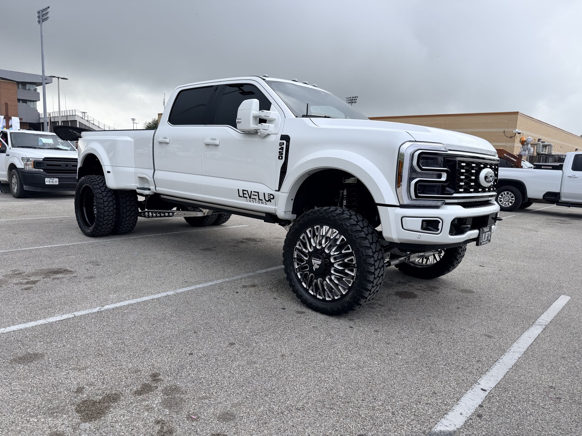 White Ford Super Duty lifted with custom chrome wheels and Level Up branding, Alvin TX
